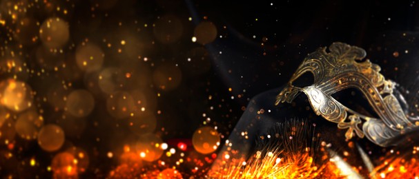 Image of Beautiful carnival mask on black background with golden glitter, bokeh effect. Banner design with space for text