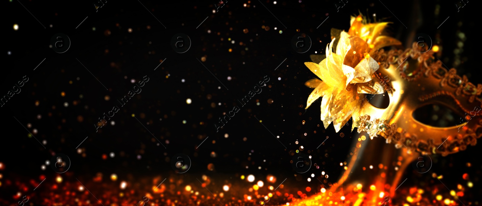 Image of Beautiful carnival mask on black background with golden glitter, bokeh effect. Banner design with space for text