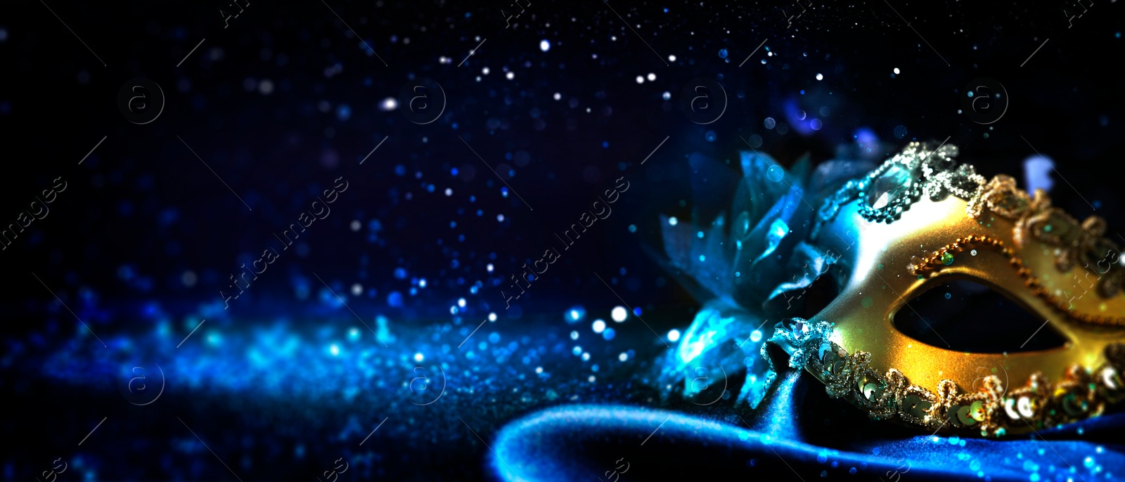 Image of Beautiful carnival mask on black background with blue light and glitter, bokeh effect. Banner design with space for text