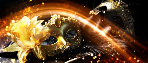 Image of Beautiful carnival masks and orange light on black background, bokeh effect. Banner design with space for text