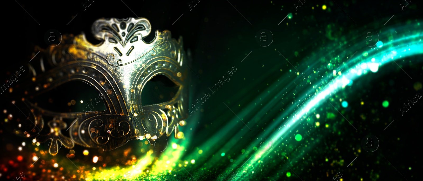 Image of Beautiful carnival mask and green light on black background with glitter, bokeh effect. Banner design with space for text