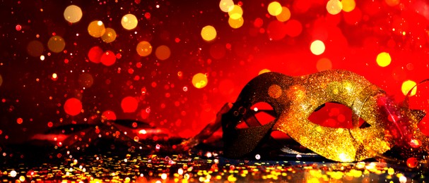 Image of Beautiful carnival mask on red background with glitter, bokeh effect. Banner design with space for text