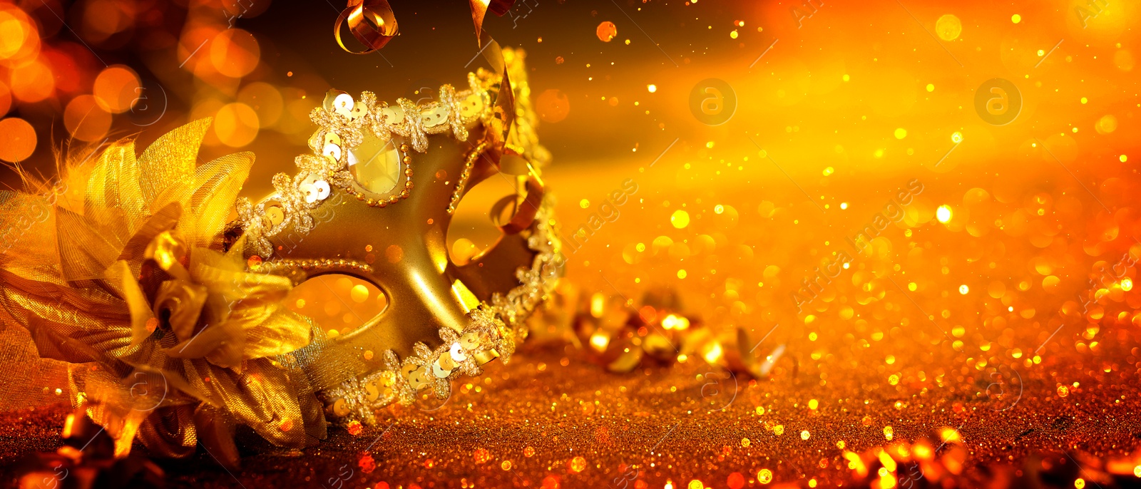 Image of Beautiful carnival mask on golden background with glitter, bokeh effect. Banner design with space for text