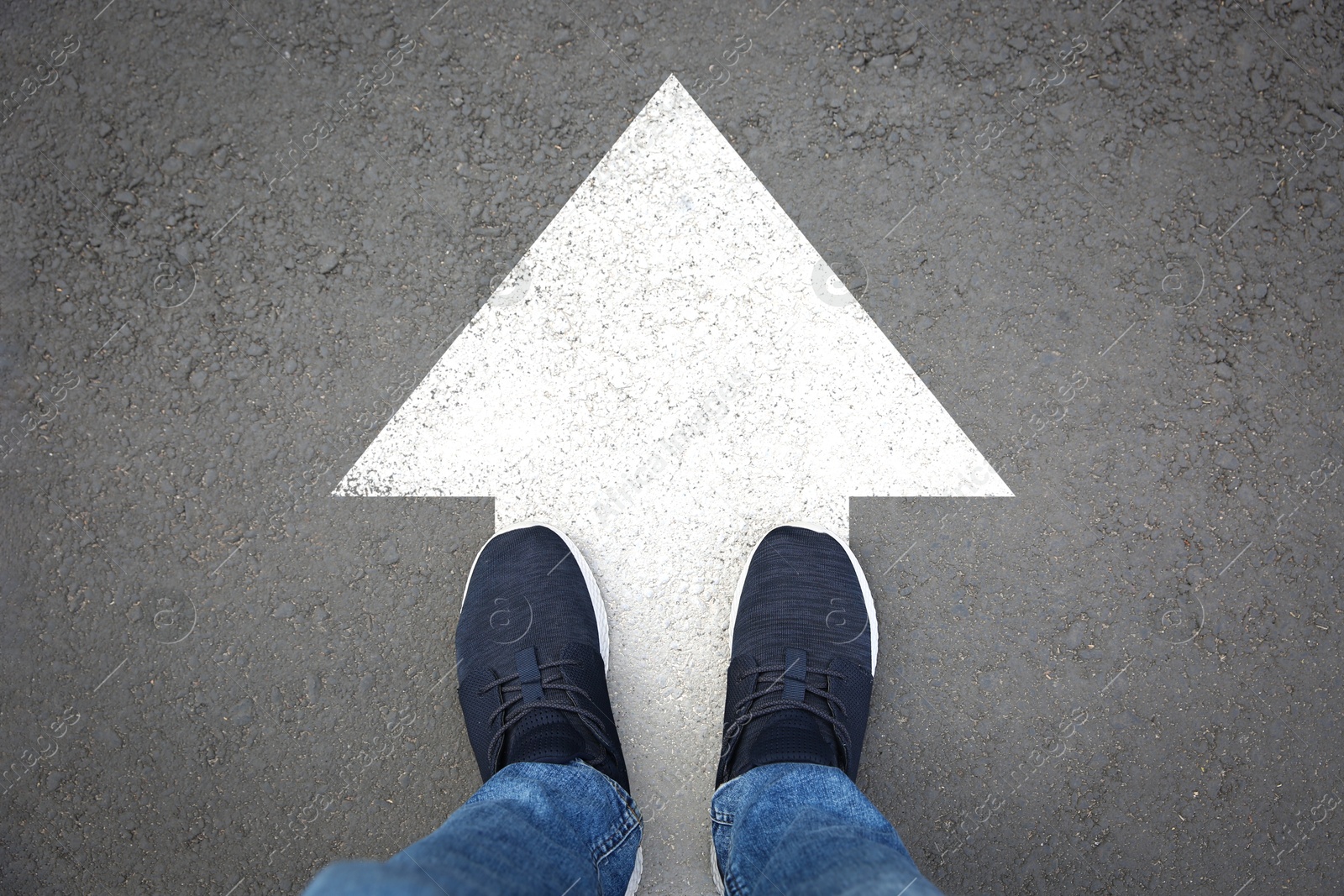 Image of Man standing on asphalt road with white arrow, top view. Move forward