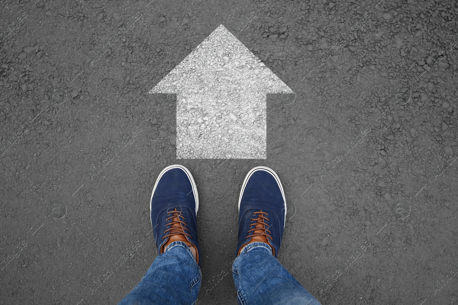 Image of Man standing near white arrow on asphalt road, top view. Move forward