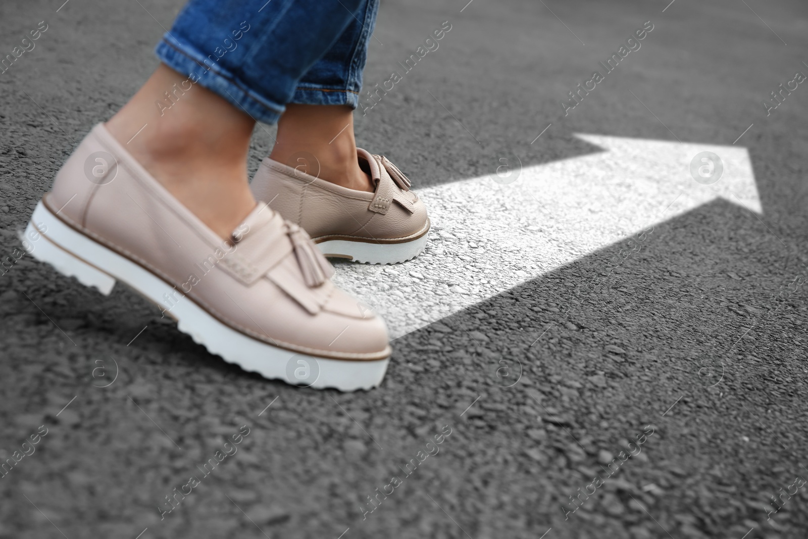 Image of Woman walking on asphalt road with white arrow, closeup. Move forward