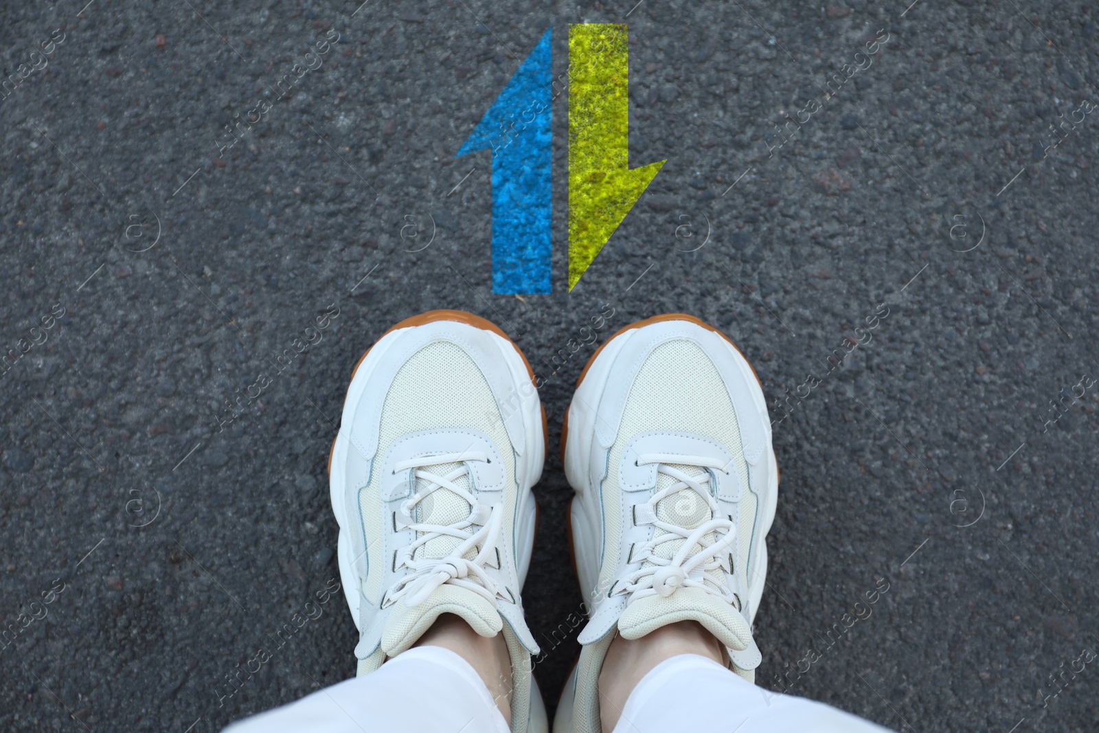 Image of Woman standing near arrows pointing in different directions on asphalt road, top view. Concept of choice and making decisions