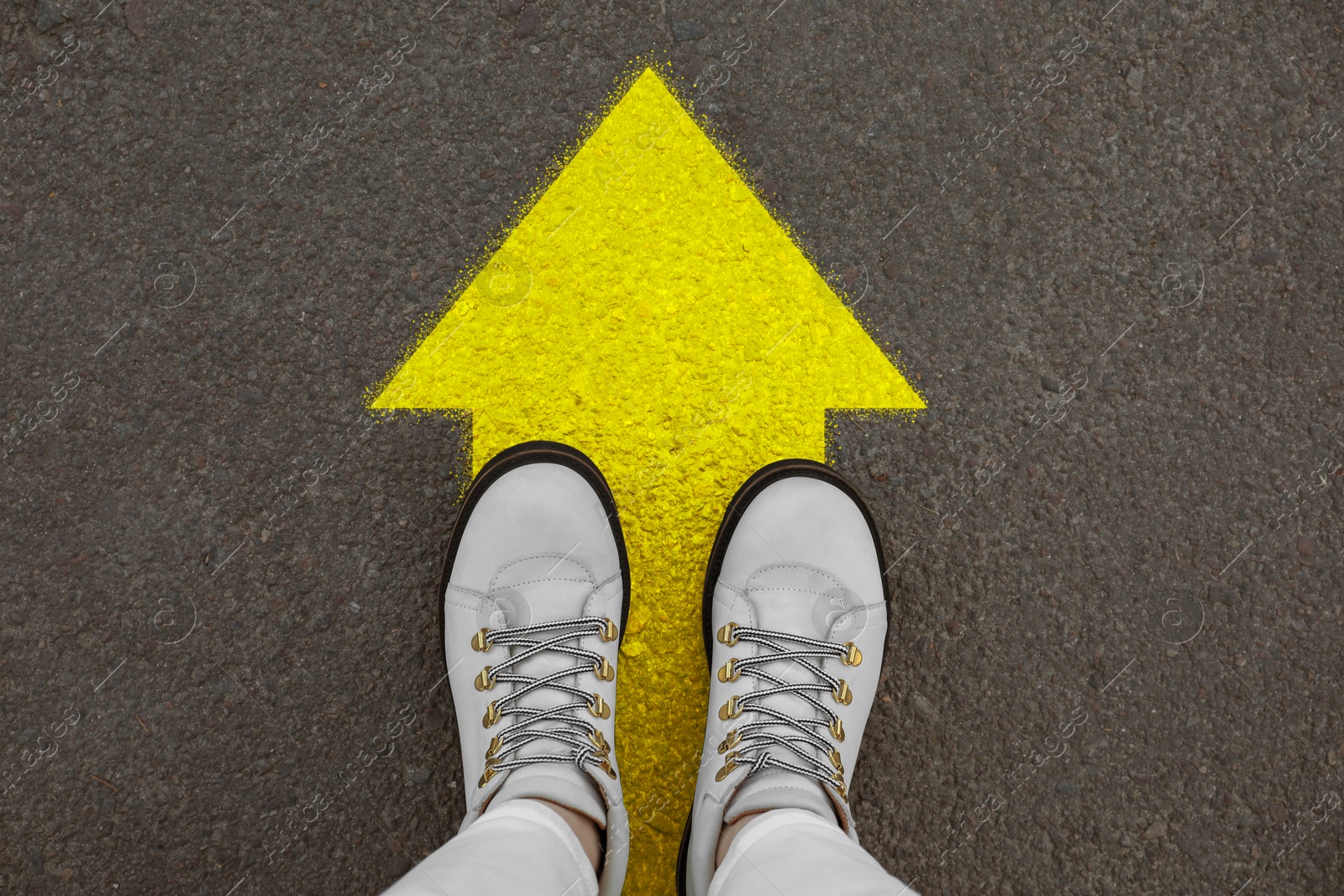 Image of Woman standing on asphalt road with yellow arrow, top view. Move forward