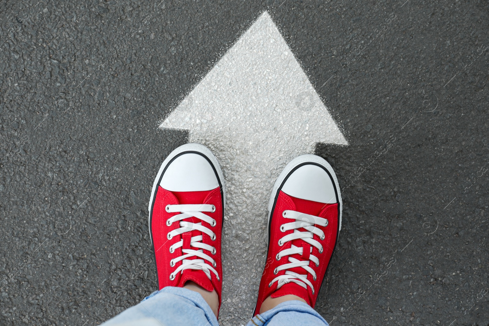 Image of Woman standing on asphalt road with white arrow, top view. Move forward