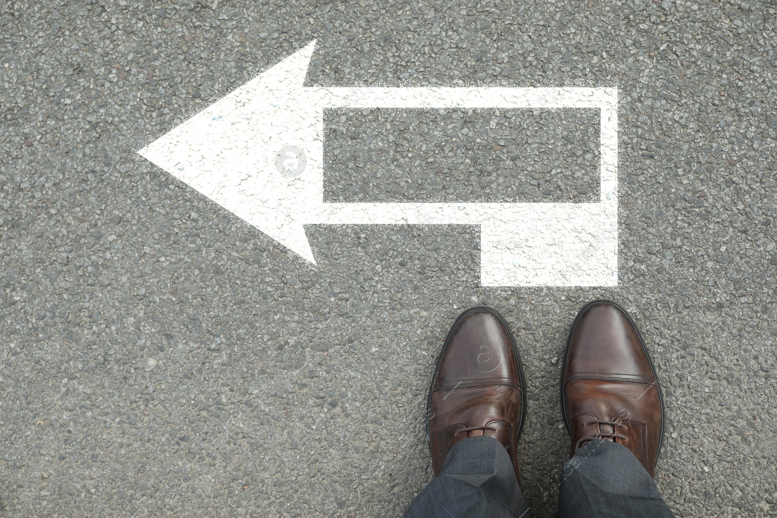 Image of Man standing near white arrow on asphalt road, top view