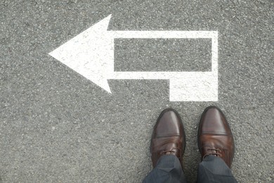 Image of Man standing near white arrow on asphalt road, top view