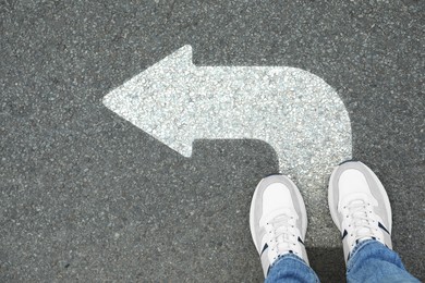 Image of Man standing on asphalt road with white arrow, top view