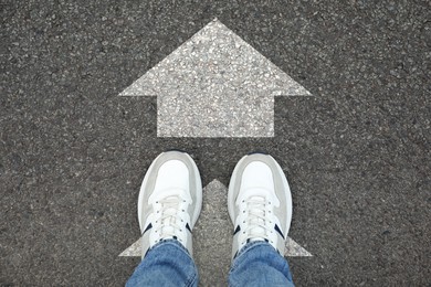 Image of Man standing on asphalt road with white arrows, top view. Move forward