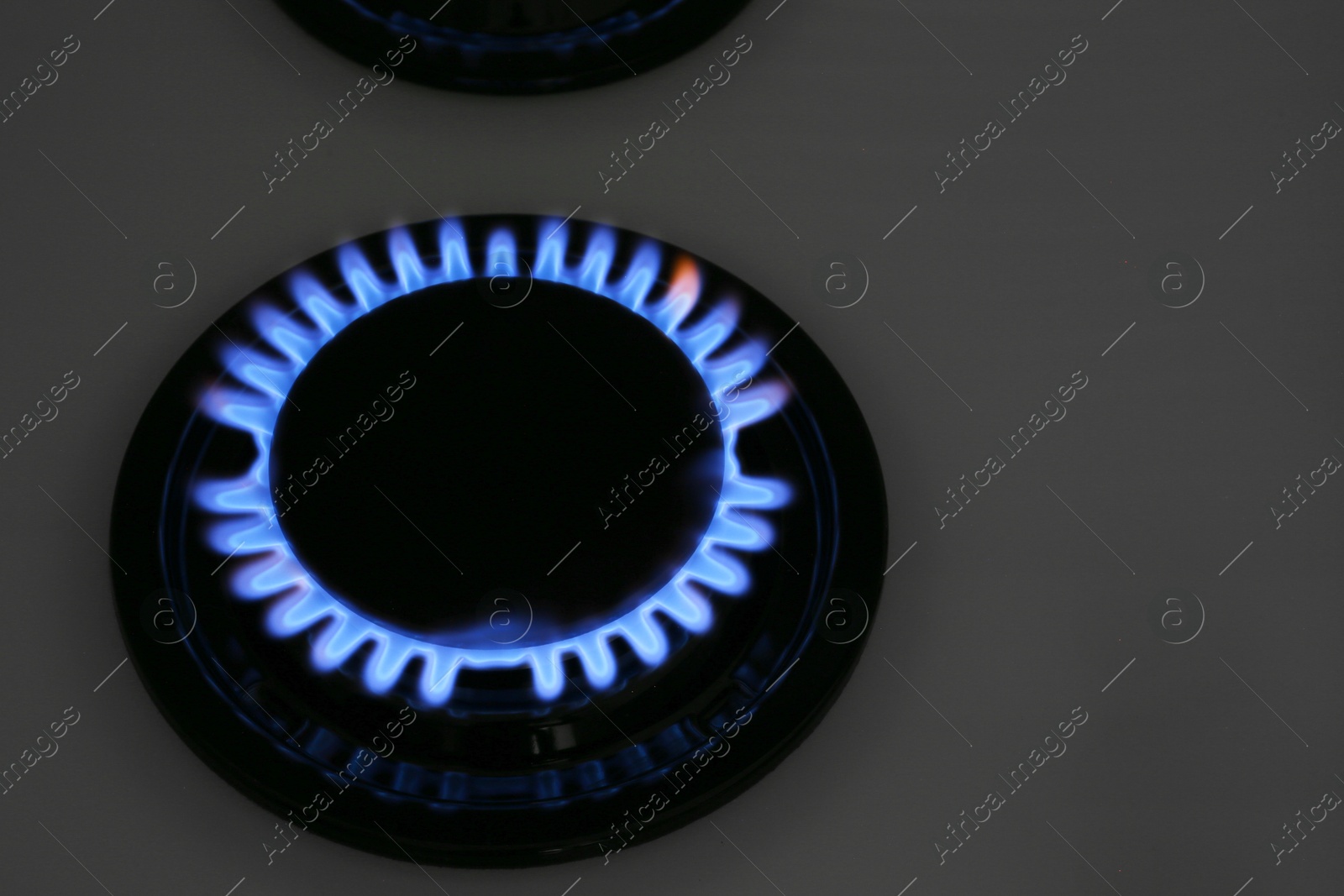 Photo of Gas burner of modern stove with burning blue flame at night