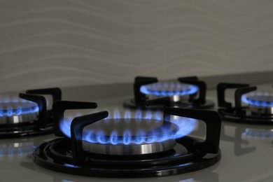 Photo of Modern gas cooktop with burning blue flames in kitchen