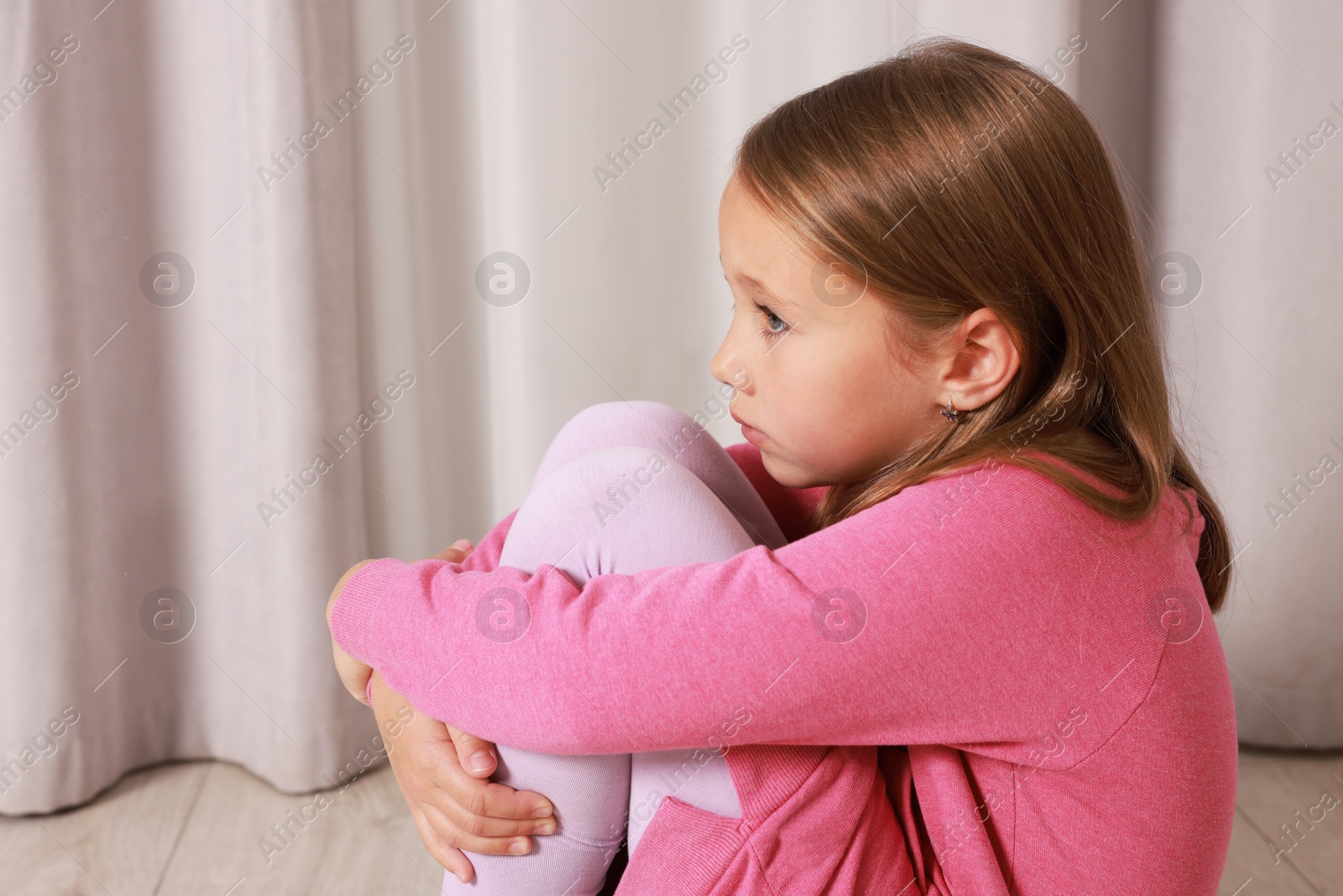 Photo of Autism concept. Lonely little girl sitting on floor at home