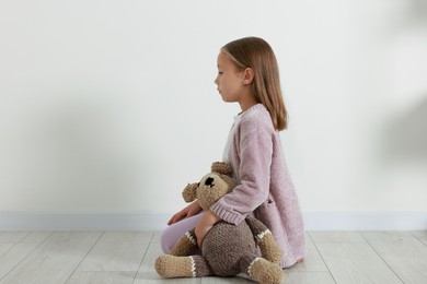 Photo of Autism concept. Lonely little girl with teddy bear on floor at home