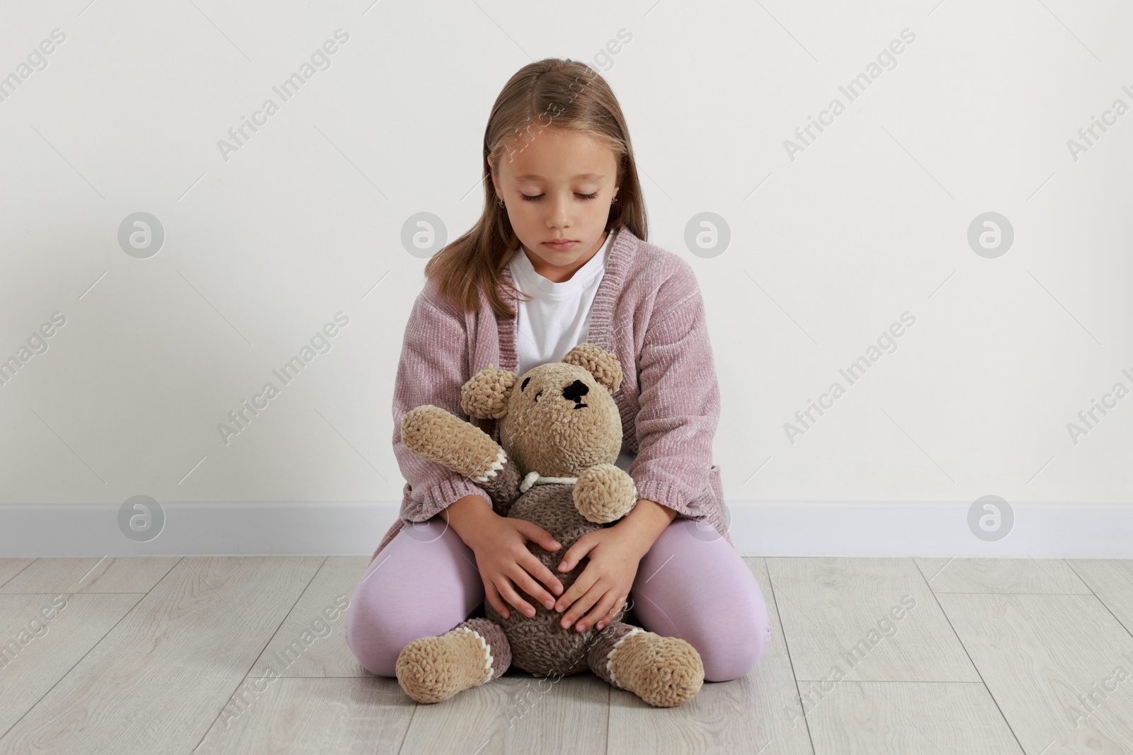 Photo of Autism concept. Lonely little girl with teddy bear on floor at home