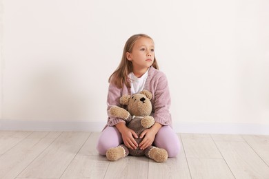 Photo of Autism concept. Lonely little girl with teddy bear on floor at home