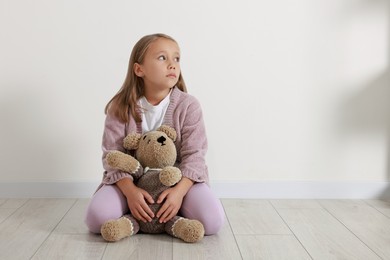 Photo of Autism concept. Lonely little girl with teddy bear on floor at home