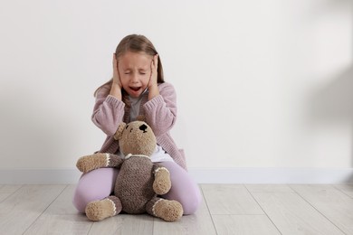 Photo of Autism concept. Scared little girl covering her ears at home, space for text