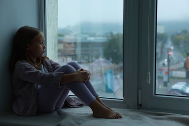 Photo of Autism concept. Lonely little girl near window at home