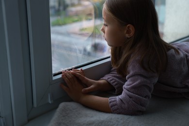 Photo of Autism concept. Lonely little girl near window at home