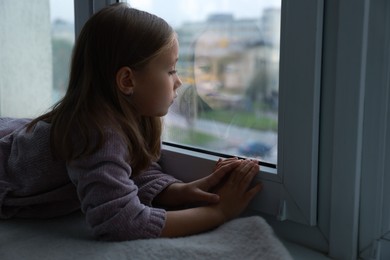 Photo of Autism concept. Lonely little girl near window at home