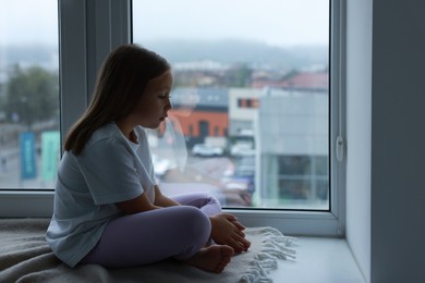 Photo of Autism concept. Lonely little girl near window at home