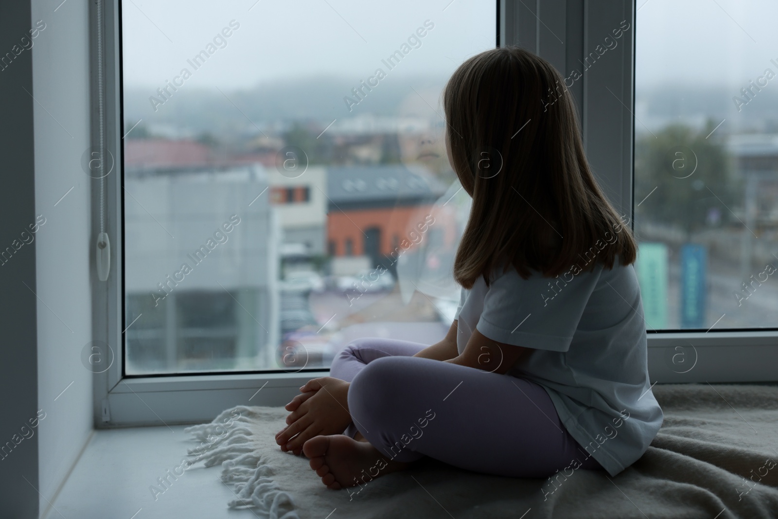 Photo of Autism concept. Lonely little girl near window at home