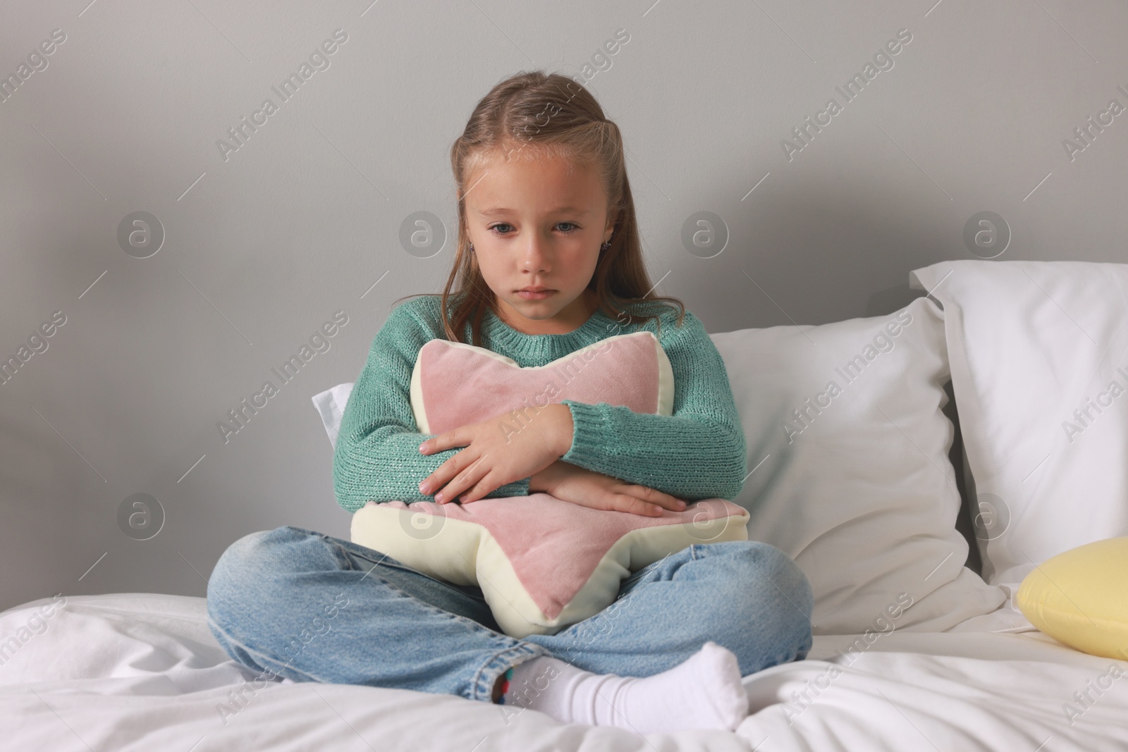 Photo of Autism concept. Lonely little girl with pillow on bed at home