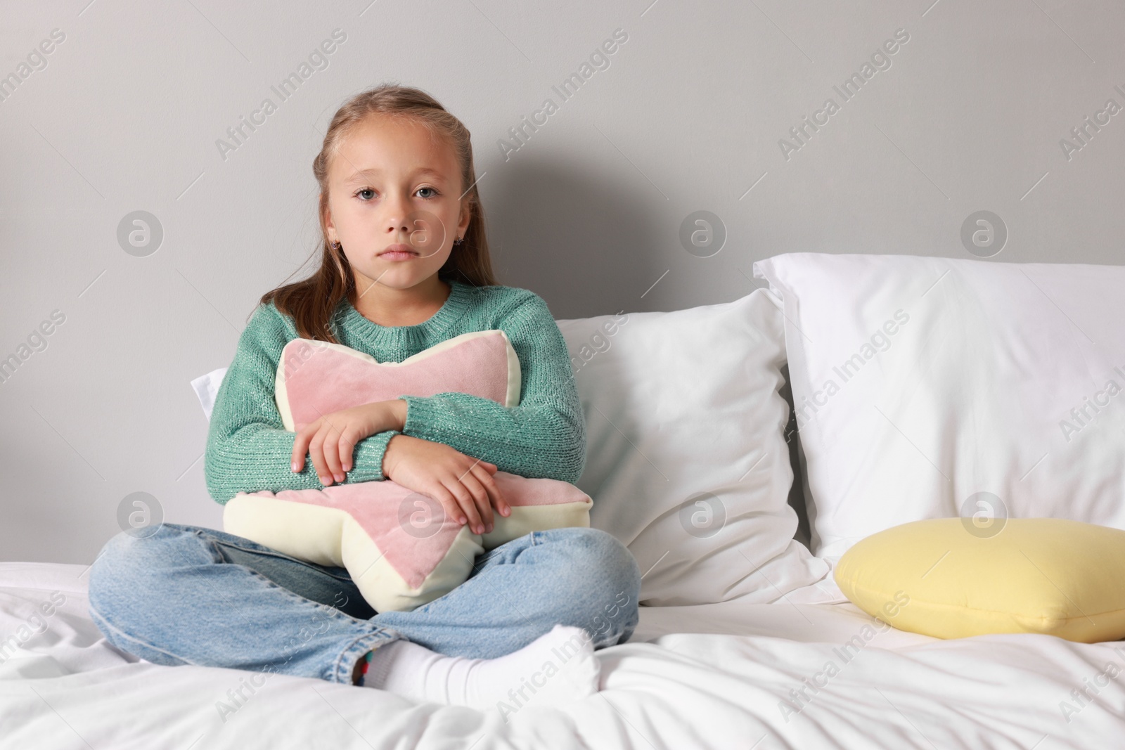 Photo of Autism concept. Lonely little girl with pillow on bed at home