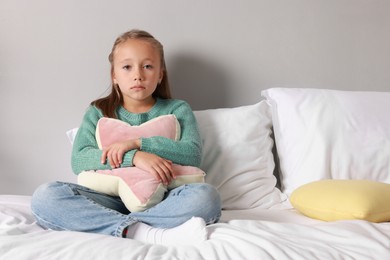 Photo of Autism concept. Lonely little girl with pillow on bed at home