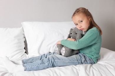 Photo of Autism concept. Lonely little girl with toy bunny on bed at home