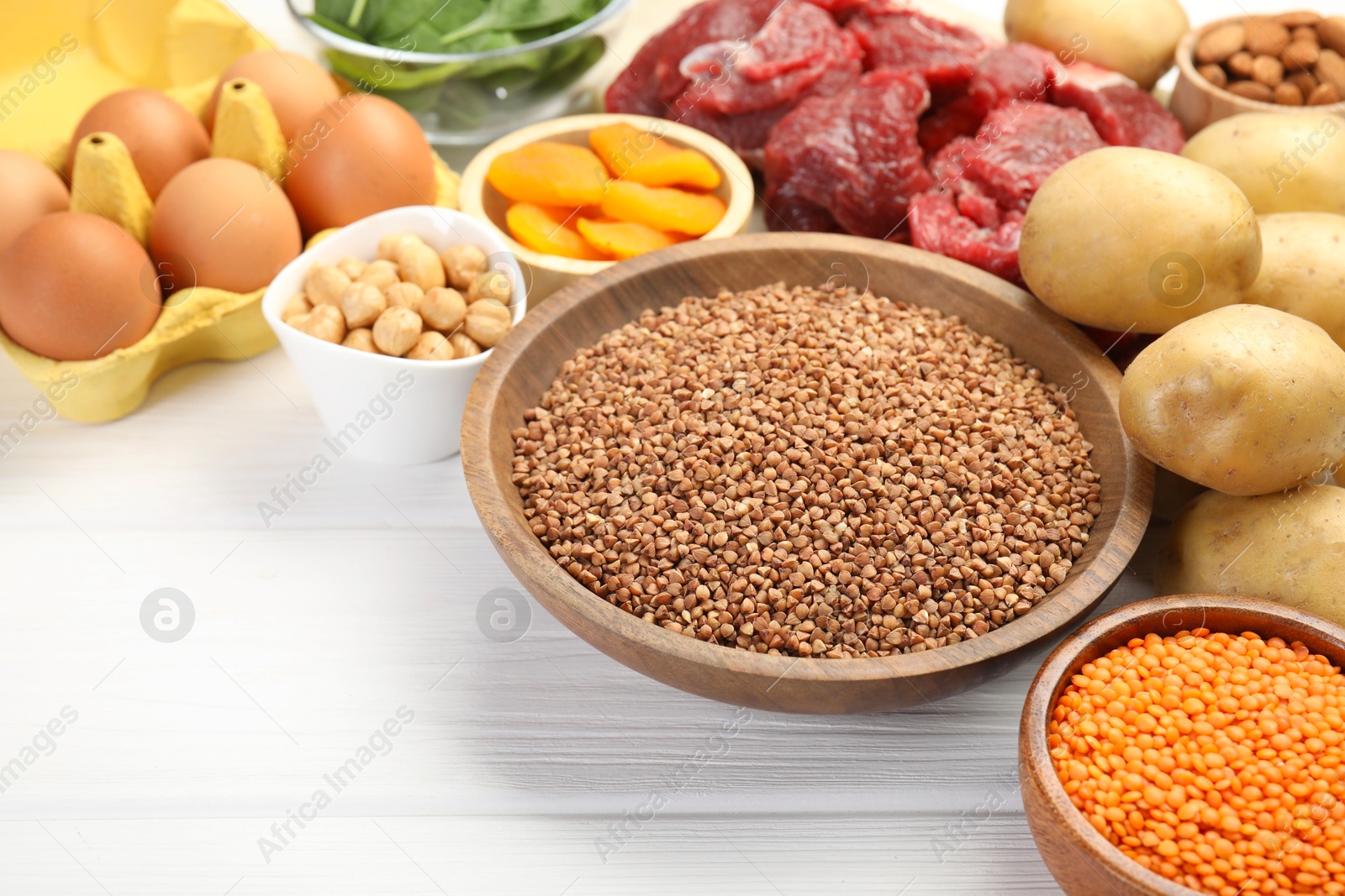 Photo of Different products rich in iron on white wooden table, closeup. Diet plan for anemia