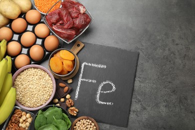 Photo of Diet plan for anemia. Different products rich in iron and slate board with Ferrum symbol on grey table, flat lay. Space for text