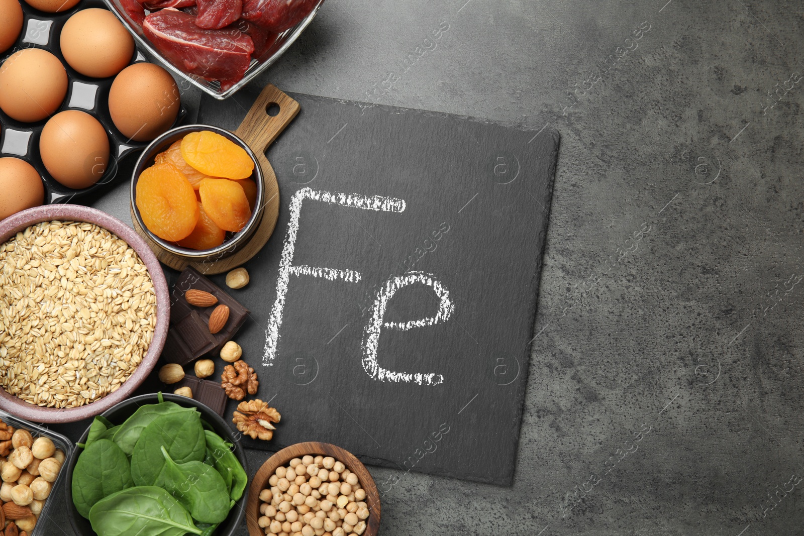 Photo of Diet plan for anemia. Different products rich in iron and slate board with Ferrum symbol on grey table, flat lay. Space for text