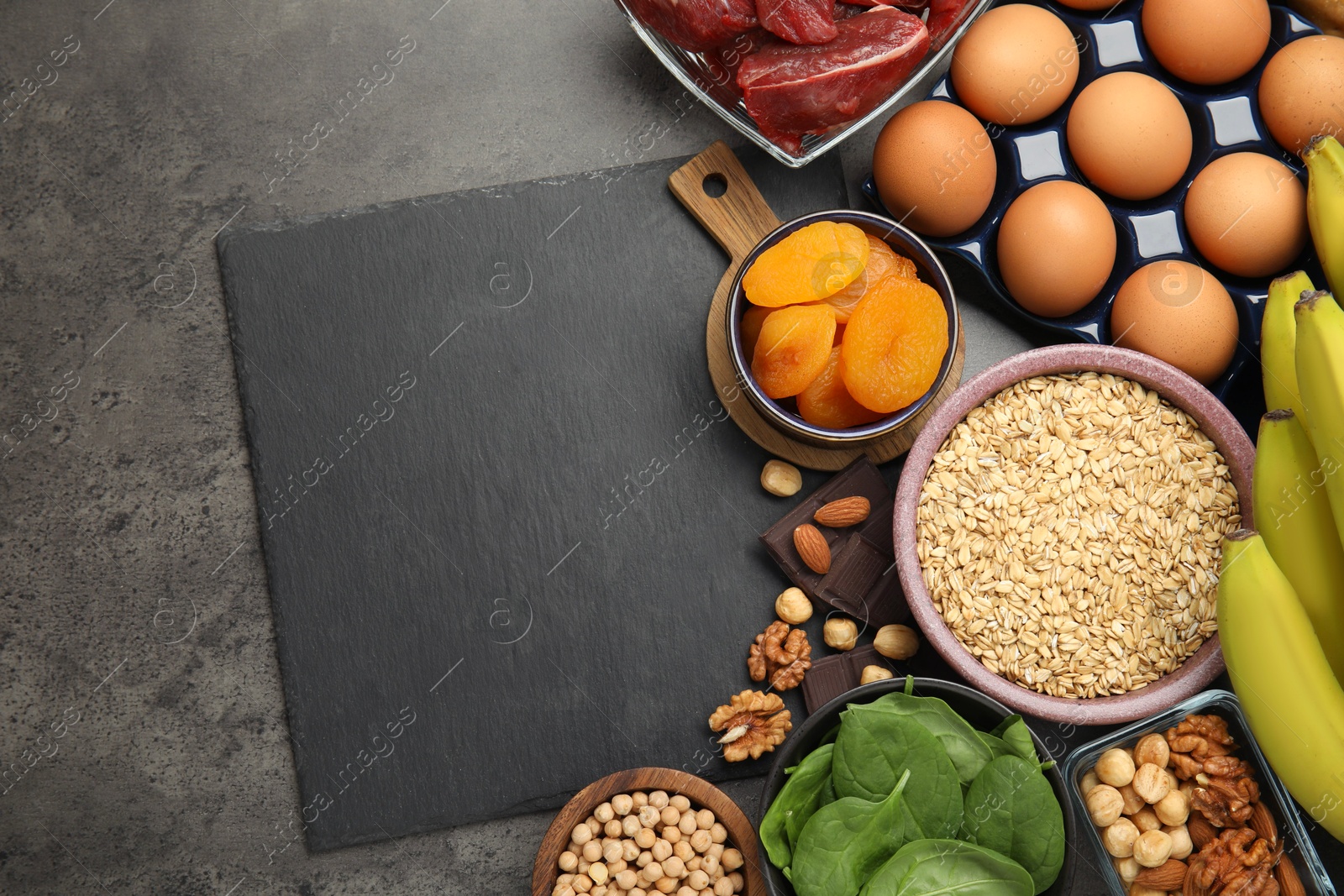 Photo of Diet plan for anemia. Different products rich in iron and slate board on grey table, flat lay. Space for text