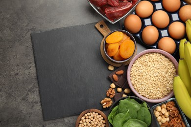 Photo of Diet plan for anemia. Different products rich in iron and slate board on grey table, flat lay. Space for text