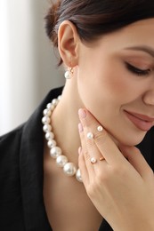 Photo of Young woman wearing elegant pearl jewelry indoors, closeup