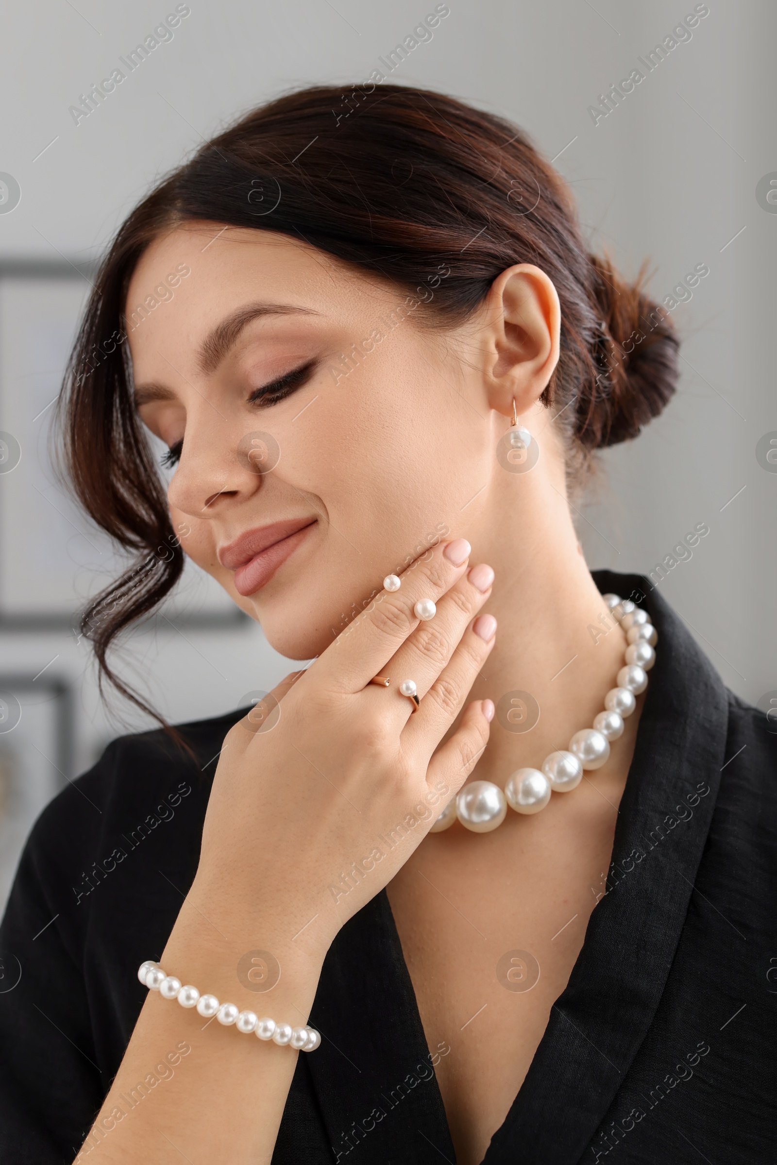 Photo of Young woman wearing elegant pearl jewelry indoors