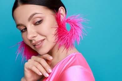 Photo of Beautiful young woman wearing stylish earrings on light blue background. Space for text