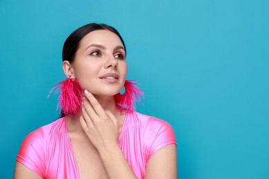 Photo of Beautiful young woman wearing stylish earrings on light blue background. Space for text