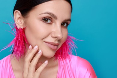 Photo of Beautiful young woman wearing stylish earrings on light blue background, closeup. Space for text