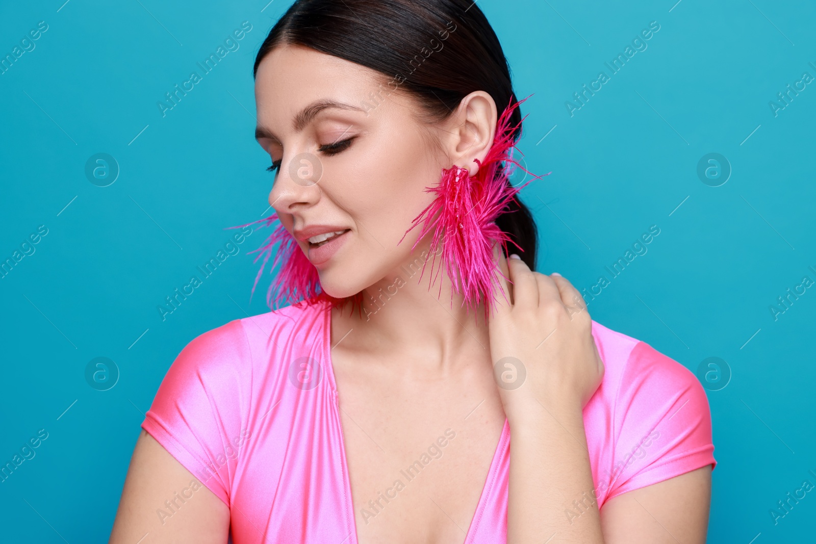 Photo of Beautiful young woman wearing stylish earrings on light blue background