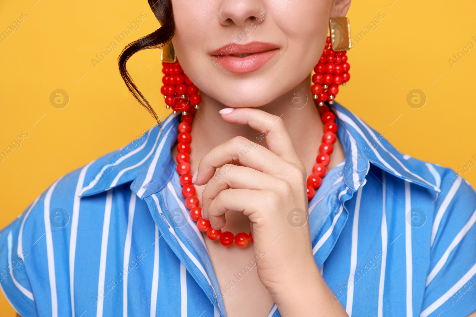 Photo of Young woman wearing stylish earrings and necklace on orange background, closeup