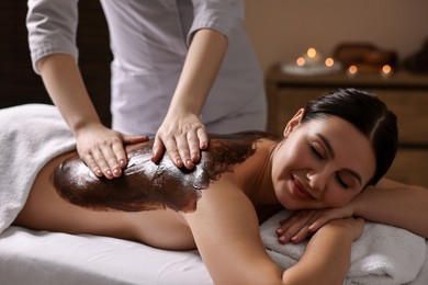 Woman undergoing chocolate body wrap treatment in spa salon