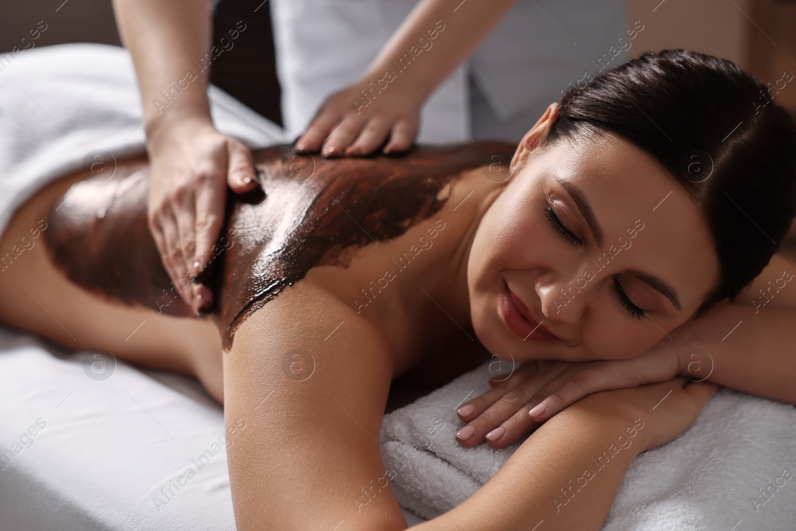 Photo of Woman undergoing chocolate body wrap treatment in spa salon