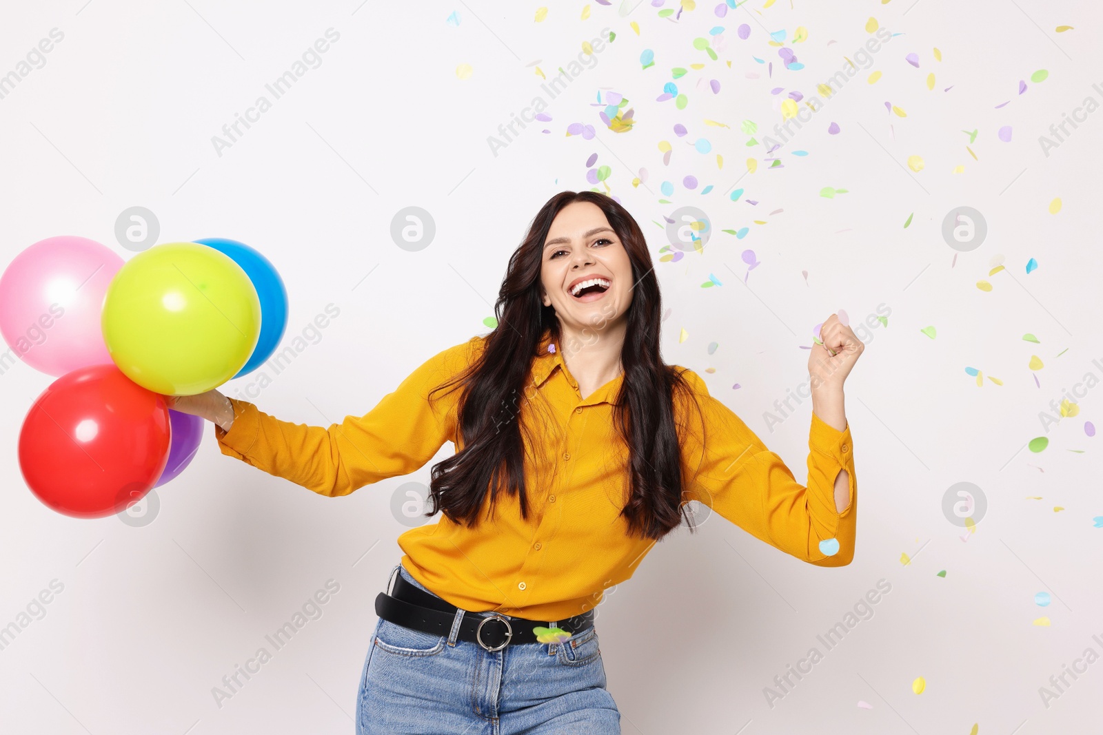 Photo of Happy woman with colorful balloons under falling confetti on white background. Surprise party