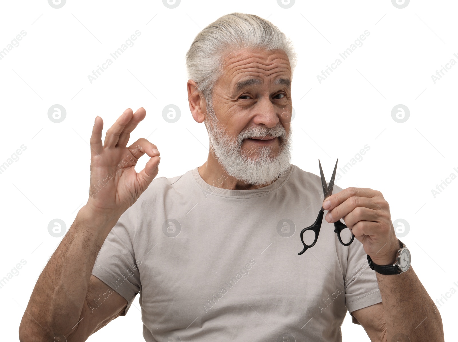 Photo of Bearded senior man with scissors showing ok gesture on white background